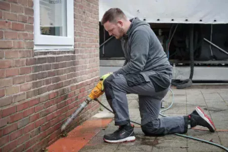 Medewerker De Vries Isolatie bezig met het uitvoeren van spouwmuurisolatie