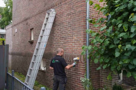 Medewerker de Vries Isolatie tijdens het impregneren van een muur