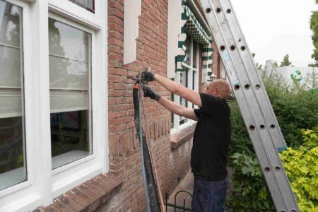 Medewerker de Vries Isolatietechniek bezig met de uitvoer van spouwmuurisolatie