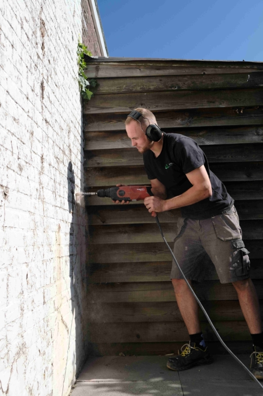 Medewerker de Vries Isolatie aan het boren tijdens spouwmuurisolatie